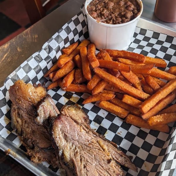 Blind Raven BBQ brisket, sweet potato fries, and baked beans on a checkered paper-lined tray.